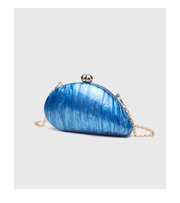 Ovale Hartschalen-Clutch in marmorierter Perlmuttoptik mit Verschluss aus zwei goldfarbenen Kugeln und goldfarbener Kettenriemen, Detailansicht