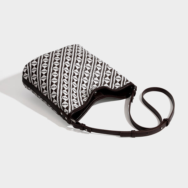 Geometrisch gemusterte Schultertasche mit gewebtem Ethno-Muster, dunkelbrauner Lederoptik-Besatzung, langem verstellbarem Riemen und kleinem herabhängendem Reißverschluss
