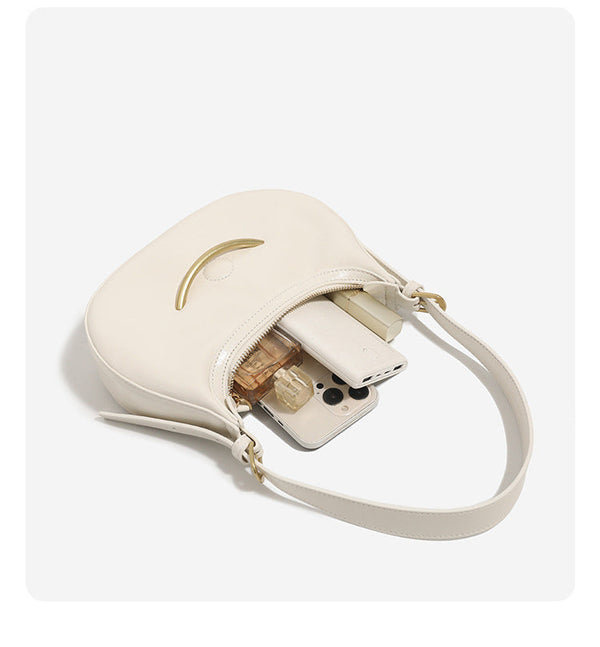 Compact crescent hobo shoulder bag with glossy synthetic finish, curved gold-tone front bar hardware, zip-top closure, and