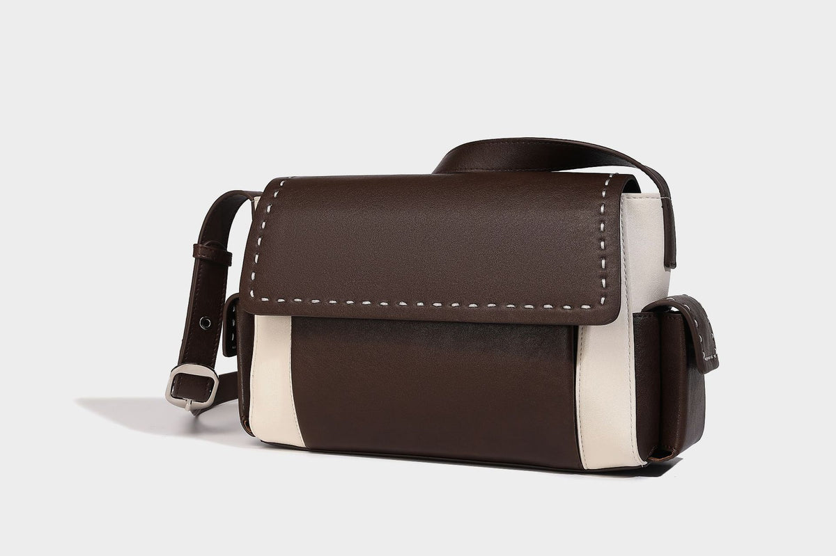 Structured flap crossbody bag in dark brown and cream color-block with white contrast stitching, adjustable shoulder strap