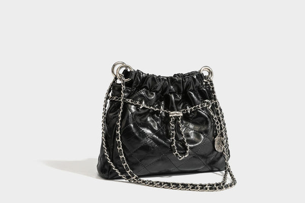 Glossy diamond-quilted drawstring bucket bag with silver chain shoulder strap and medallion charm, detail view 33