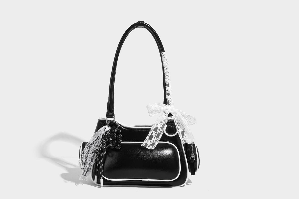Kleine, formstabile Schultertasche mit glänzender Oberfläche, weißem Paspelbesatz, Spitzenschleife und rotem Perlenanhänger, Reißverschluss-Seitentaschen und silberfarbenem