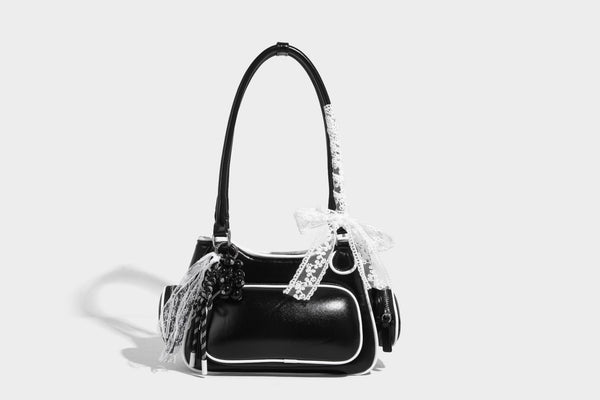 Kleine, formstabile Schultertasche mit glänzender Oberfläche, weißem Paspelbesatz, Spitzenschleife und rotem Perlenanhänger, Reißverschluss-Seitentaschen und silberfarbenem