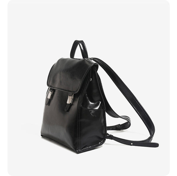 Structured glossy leather-look flap backpack handbag with dual buckle closures, top handle, and silver-tone hardware, detail