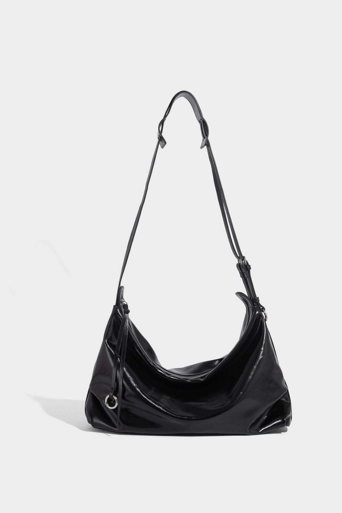 Glossy black slouchy hobo shoulder bag with zip closure, silver-tone ring hardware, and adjustable crossbody strap, detail