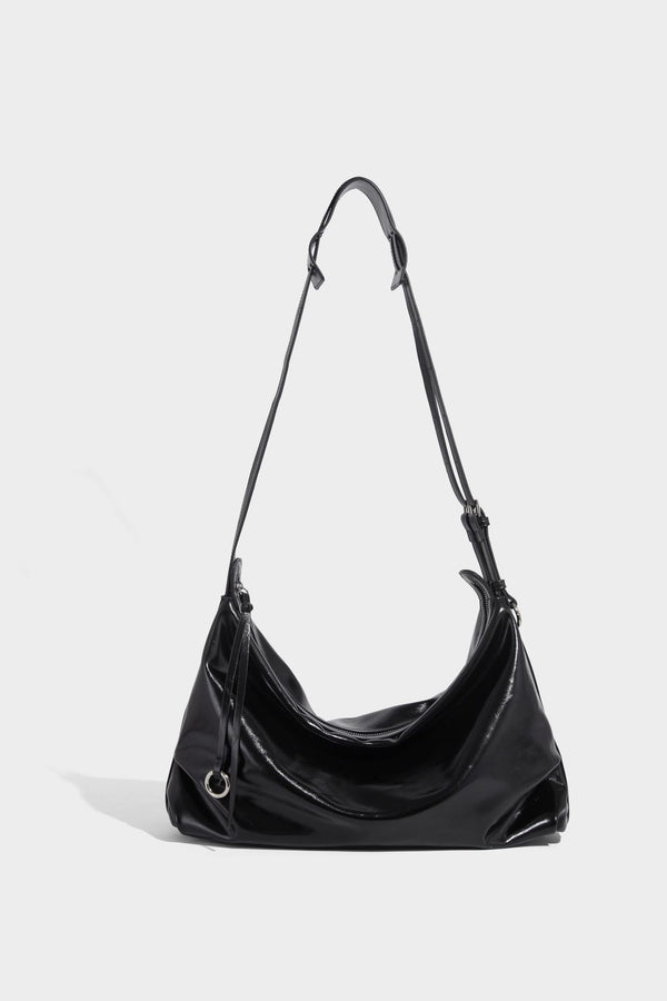 Glossy black slouchy hobo shoulder bag with zip closure, silver-tone ring hardware, and adjustable crossbody strap, detail