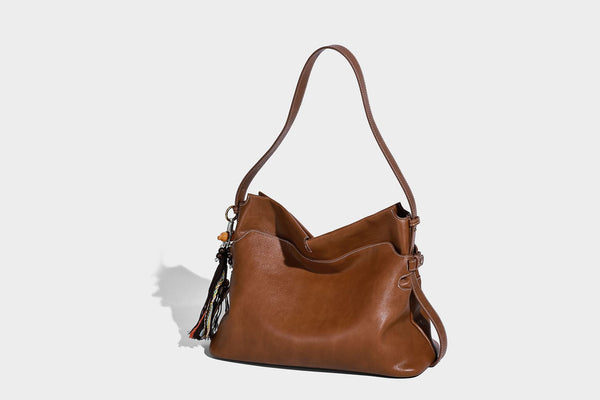 Large slouchy leather-look hobo tote bag with open top, adjustable shoulder strap, and colorful tassel bead charm, detail