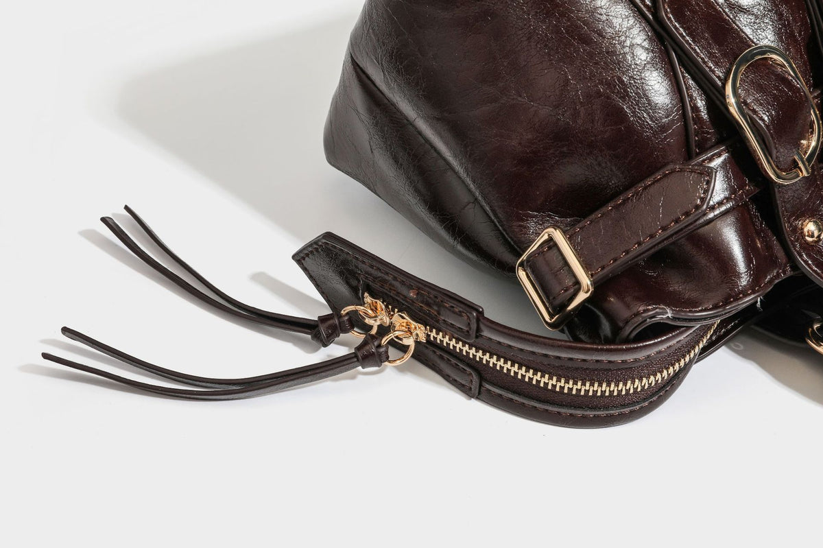 Glossy dark brown structured Boston satchel with heart-shaped lock charm, star pendant, rivet studs, multi-strap front panel