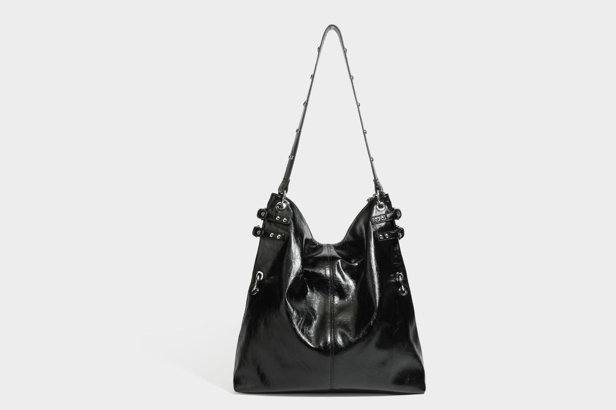 Black glossy leather-look slouchy shoulder bag with silver stud and eyelet hardware, top zip closure, front zip pocket, and