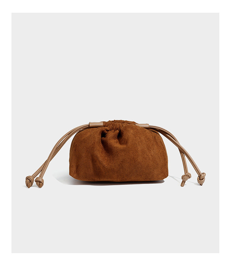 Pebbled leather-look bucket tote bag with rolled double handles, drawstring closure, braided cord charm, and detachable
