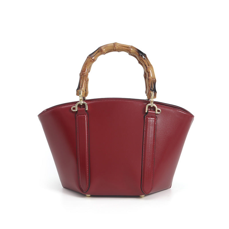 Structured trapezoid handbag with segmented bamboo top handle, smooth leather-look finish, gold-tone hardware, and vertical