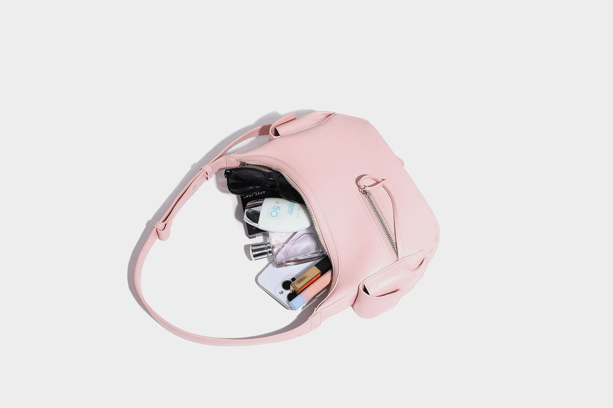 Smooth leather-look crescent shoulder bag with front zip pocket, side flap pockets, adjustable strap, and silver-tone, detail
