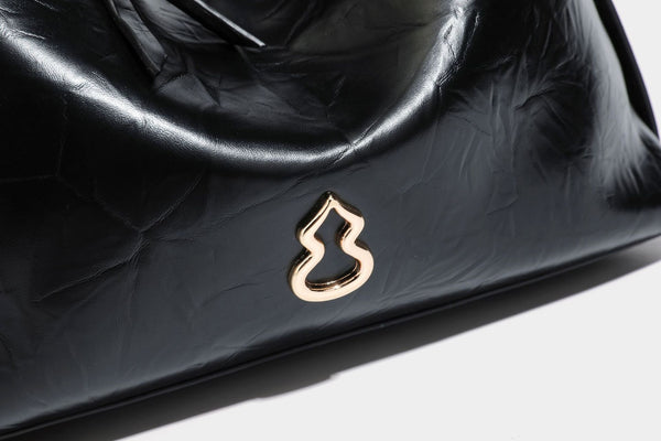 Übergroße, lässig fallende Hobo-Schultertasche aus glänzendem, geknittertem Lederimitat mit goldfarbenem Reißverschluss und Emblem-Beschlägen, Detailansicht