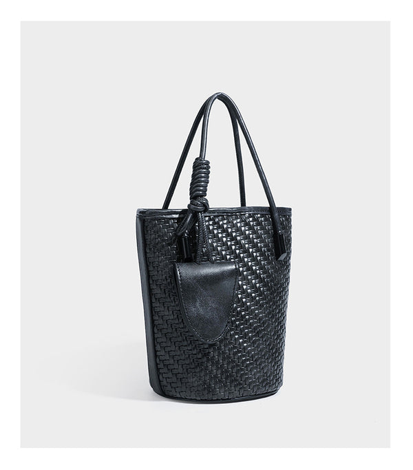 Structured woven-texture leather-look bucket bag in brown with knotted top handles, small front flap pouch, and adjustable