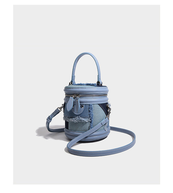 Mini cylindrical barrel bucket bag in denim patchwork with frayed edges, smooth leather-look trim, zip-around top closure