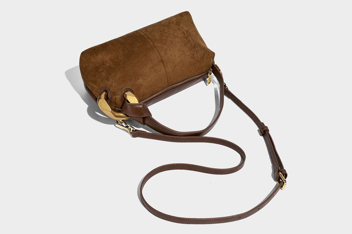 Kompakte Boston-Schultertasche in warmem Braun in Wildlederoptik mit glattem dunkelbraunem Besatz, übergroßen goldfarbenen Ringelementen und Reißverschluss oben