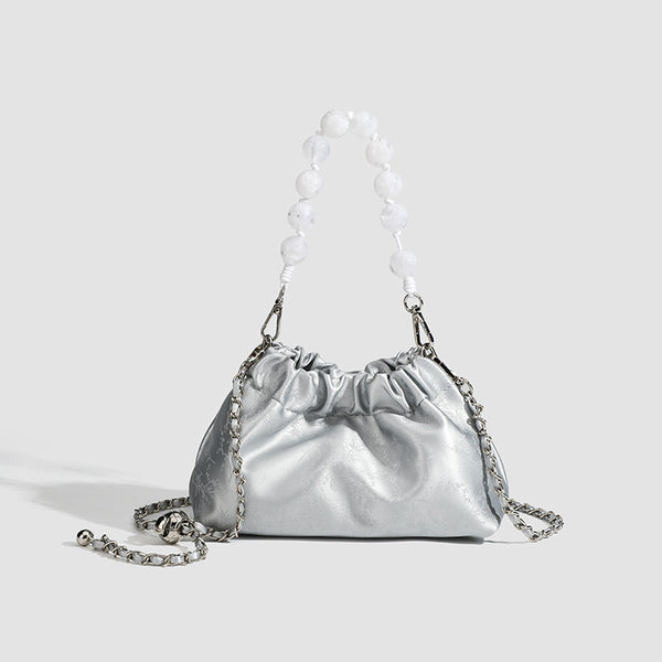 Small ruched drawstring pouch bag with pearl-bead handle and silver-tone chain strap, front view