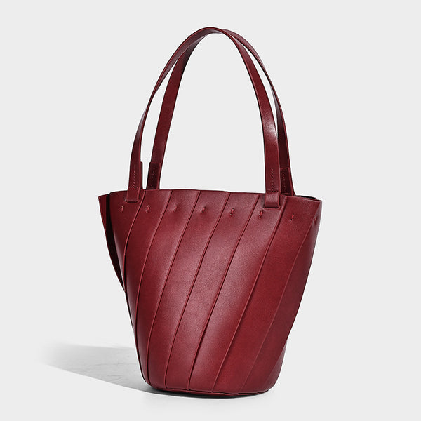 Structured bucket tote bag with vertical panel exterior, dual top handles, and detachable shoulder strap in tan leather-look