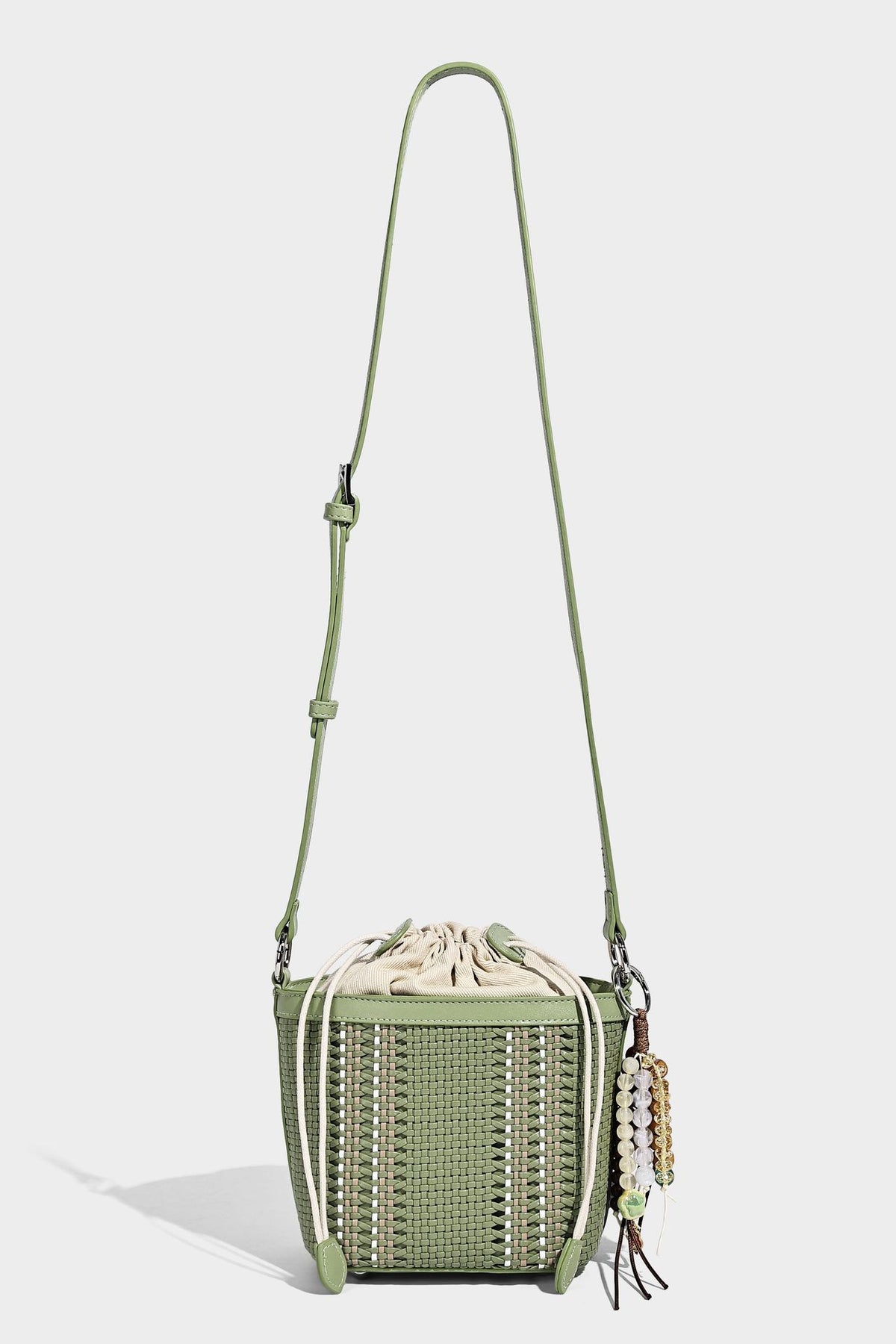 Small woven bucket bag with drawstring top, braided handle, detachable crossbody strap, and silver-tone ring hardware, detail