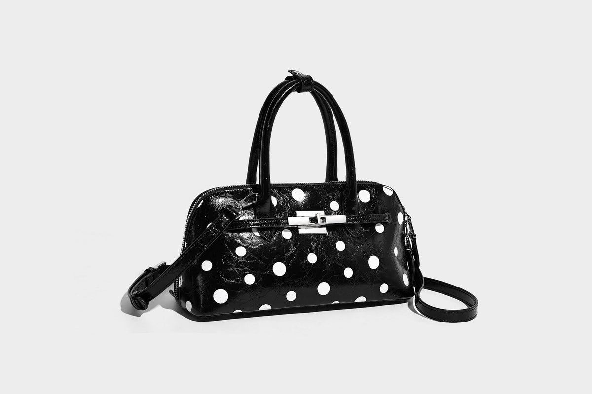 Glossy structured polka-dot satchel bag with dual top handles, silver turn-lock hardware, and detachable shoulder strap
