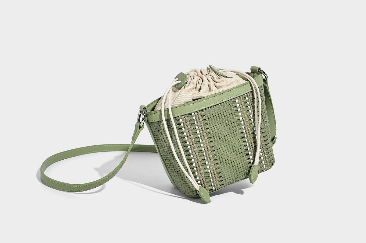 Small woven bucket bag with drawstring top, braided handle, detachable crossbody strap, and silver-tone ring hardware, detail