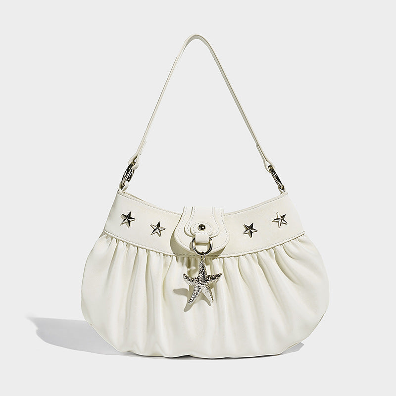 Ruched shoulder bag with curved flap, silver star studs, dangling starfish charm, and adjustable crossbody strap, detail view