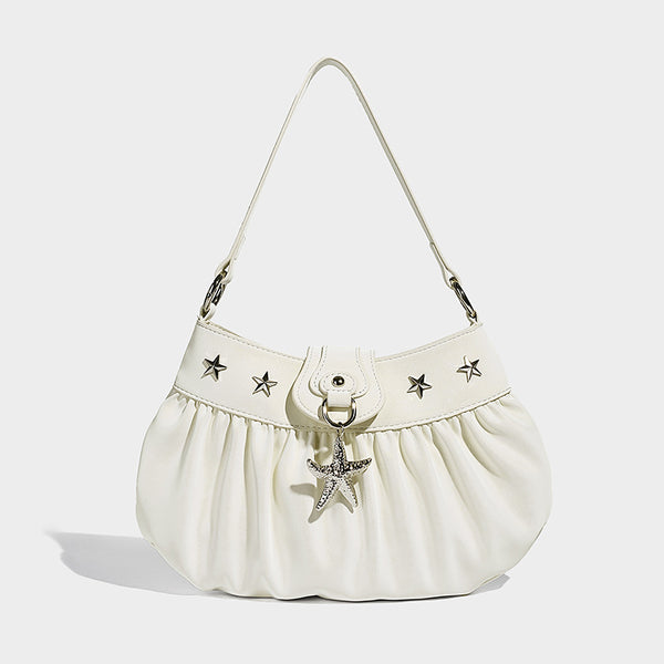 Ruched shoulder bag with curved flap, silver star studs, dangling starfish charm, and adjustable crossbody strap, detail view