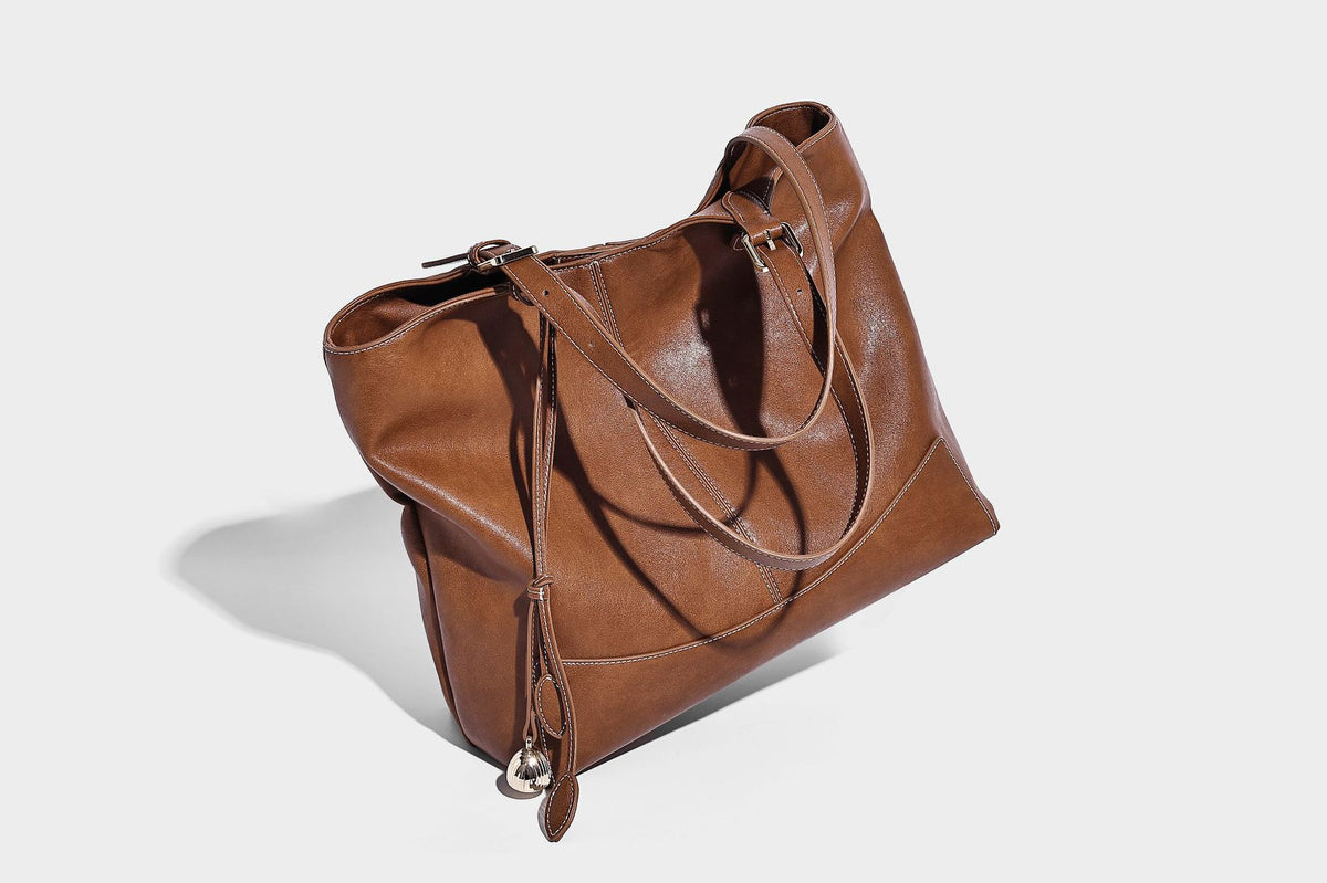 Große, strukturierte Schultertasche im Tote-Stil in Braun und Lederoptik mit langen Doppelriemen, Schnallenbeschlägen, Quasten-Anhänger und geschwungener