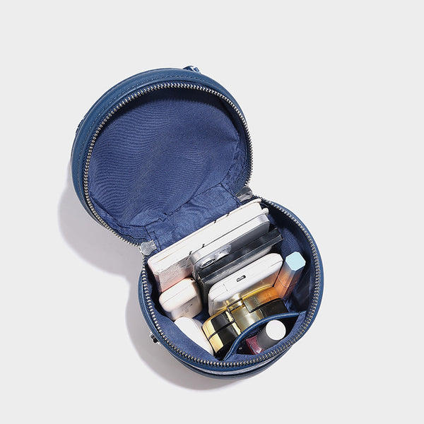 Small cylindrical barrel bag in blue-and-white floral jacquard with leather-look trim, scarf-wrapped top handle, silver-tone
