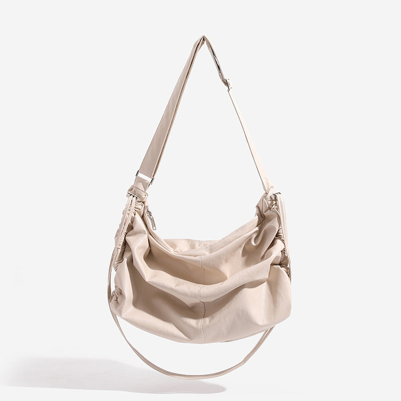 Oversized slouchy hobo shoulder bag with glossy crinkled leather-look finish, drawstring gathered sides, and silver-tone