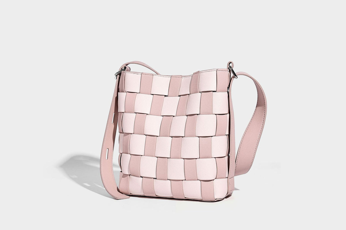 Hand-woven black-and-white checkerboard bucket bag with smooth black trim, silver-tone ring hardware, and adjustable
