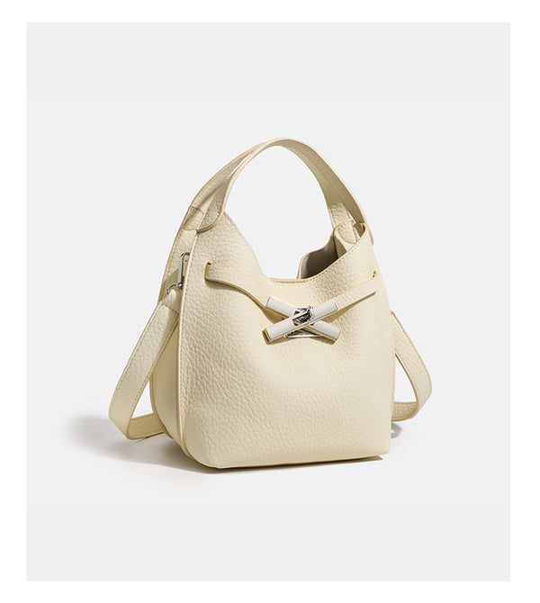 Compact pebbled leather-look shoulder bag with crossed silver-toned metal front closure, short top handle, and long, detail