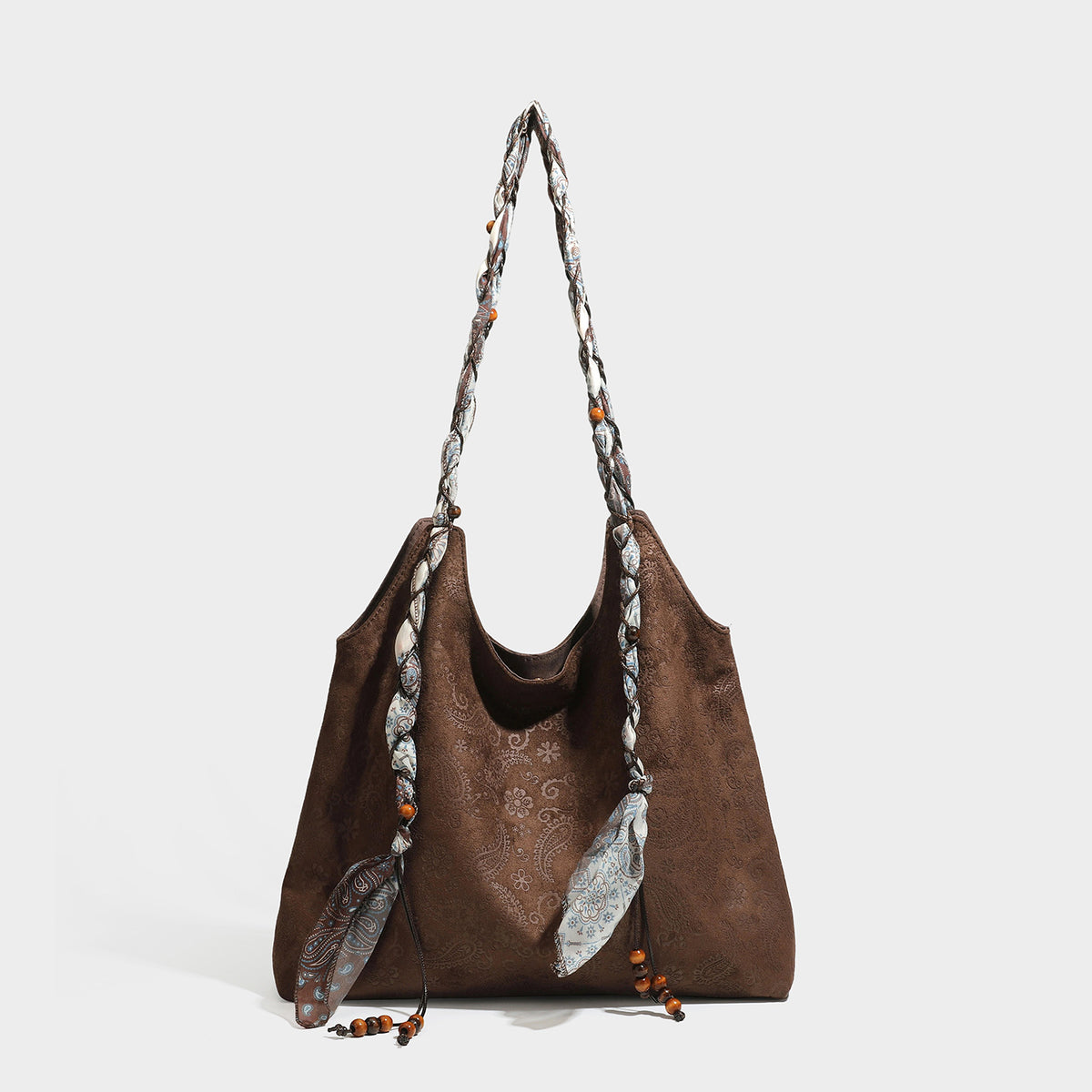 Slouchy paisley-embossed suede-look shoulder tote bag with braided patterned fabric straps and wood bead accents, detail view