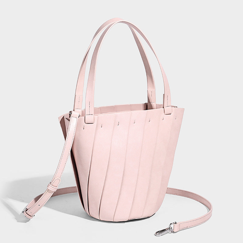 Structured bucket tote bag with vertical panel exterior, dual top handles, and detachable shoulder strap in tan leather-look