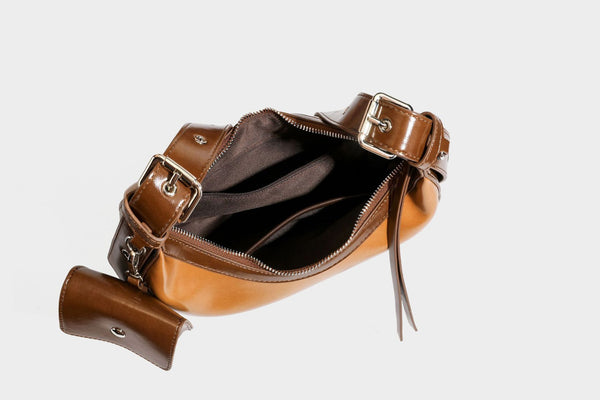 Glossy leather-look crescent hobo shoulder bag with dark contrast trim, silver-tone hardware, and attached mini flap pouch