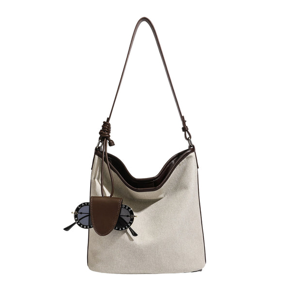 Cremefarbene Canvas-Beuteltasche mit dunkelbraunem Besatz in Lederoptik, geknotetem Riemen und befestigter Mini-Tasche, Detailansicht 6