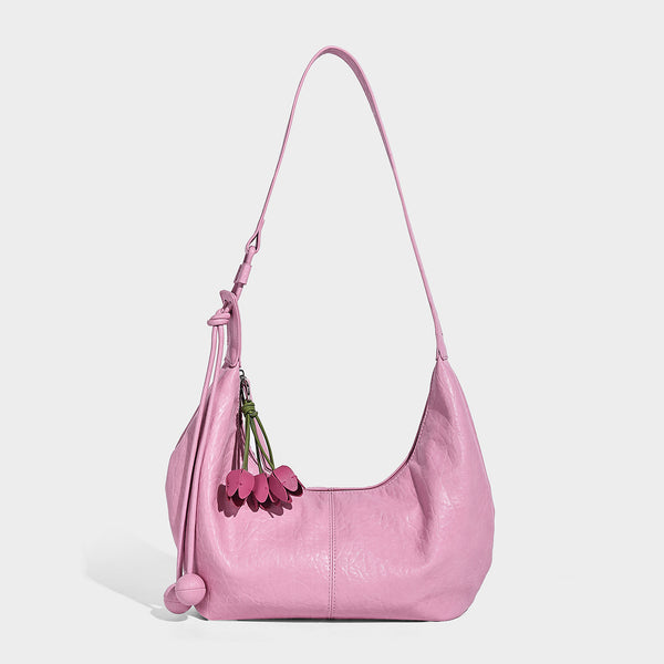 Slouchy crescent half-moon shoulder bag in pink pebbled textured finish with floral charm and knotted side detail, detail