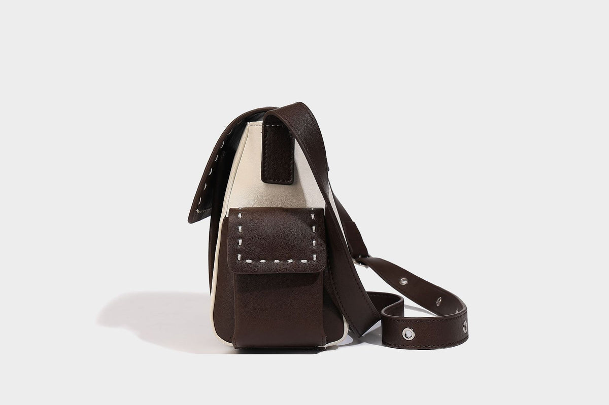 Structured flap crossbody bag in dark brown and cream color-block with white contrast stitching, adjustable shoulder strap