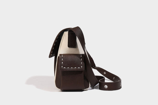 Structured flap crossbody bag in dark brown and cream color-block with white contrast stitching, adjustable shoulder strap