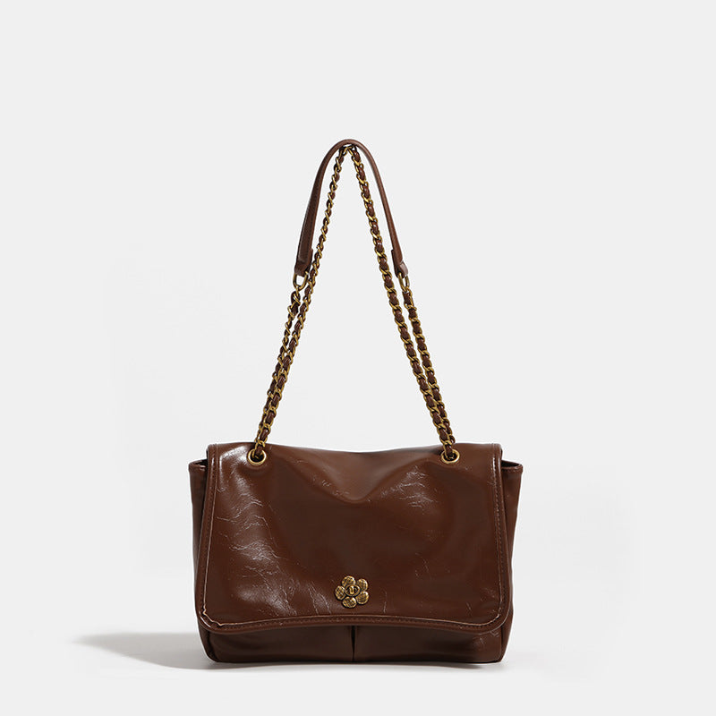 Structured flap shoulder bag with antique gold-tone chain strap and flower turn-lock clasp in crinkled leather-look finish
