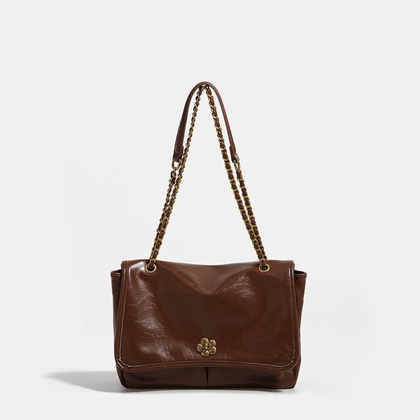 Structured flap shoulder bag with antique gold-tone chain strap and flower turn-lock clasp in crinkled leather-look finish