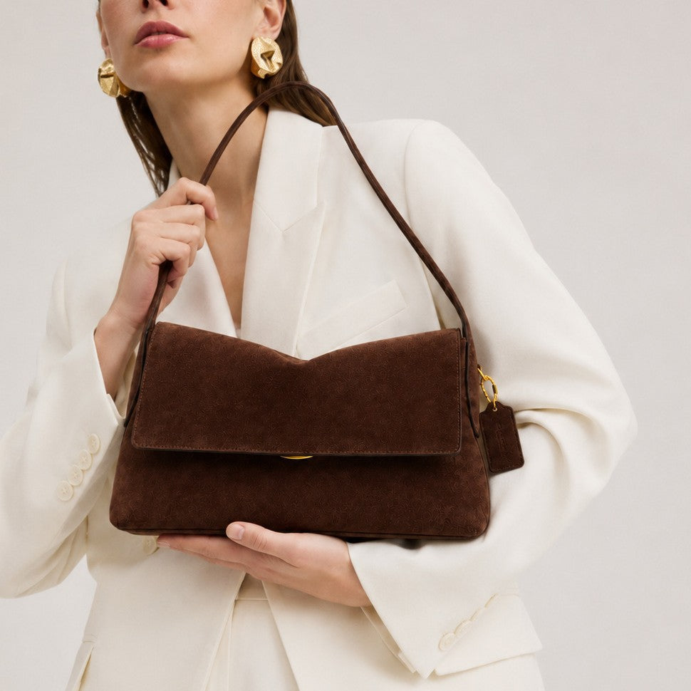 Rectangular matte suede-finish flap shoulder bag with slim dark strap and gold-tone turn-lock hardware, front view