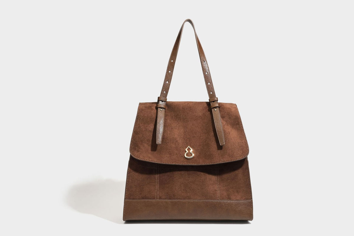 Structured suede-look convertible backpack handbag with flap closure and gold-tone emblem hardware in chocolate brown, detail
