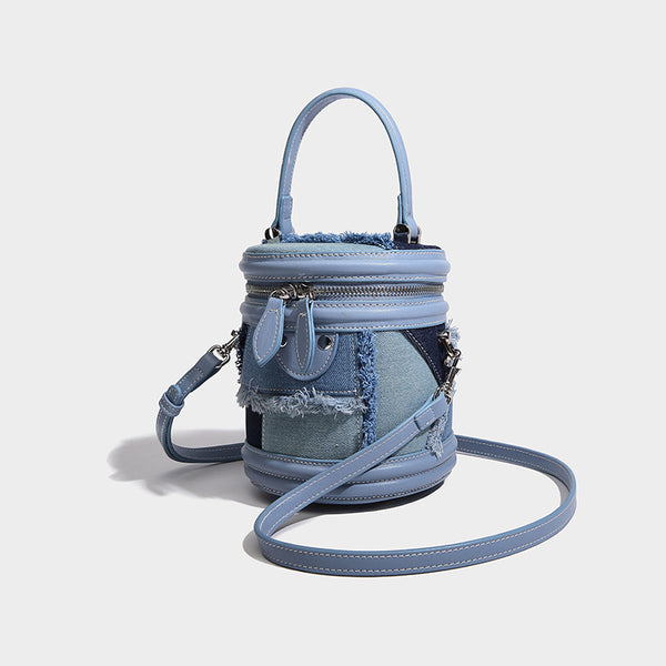Mini cylindrical barrel bucket bag in denim patchwork with frayed edges, smooth leather-look trim, zip-around top closure