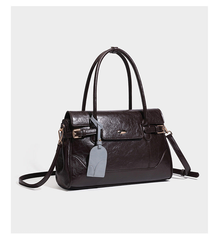 Structured glossy leather-look satchel bag with flap closure, gold-tone buckle accents, double top handles, detachable