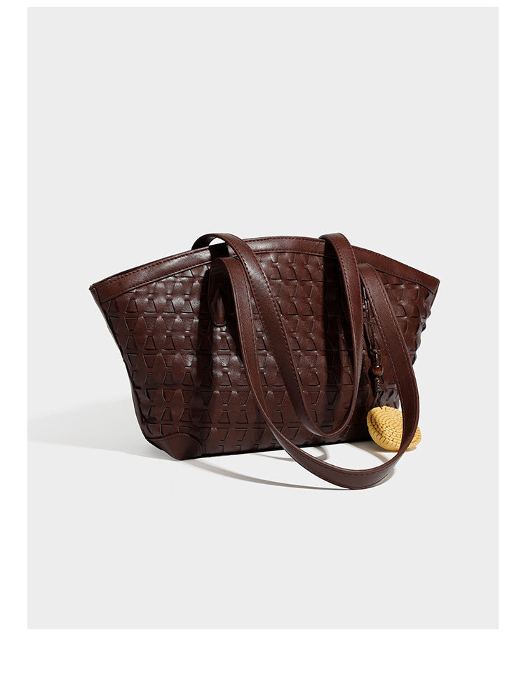 Large leather-look tote bag with geometric woven emboss, double shoulder straps, and round woven cord charm in brown, detail