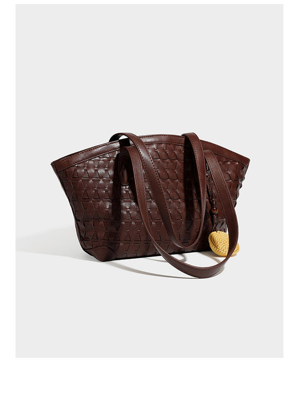 Large leather-look tote bag with geometric woven emboss, double shoulder straps, and round woven cord charm in brown, detail
