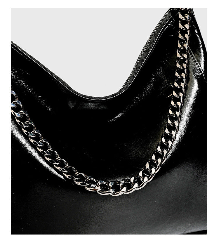 Slouchy hobo shoulder bag with glossy leather-look finish, silver-tone chain drape across front, side buckle pockets, and