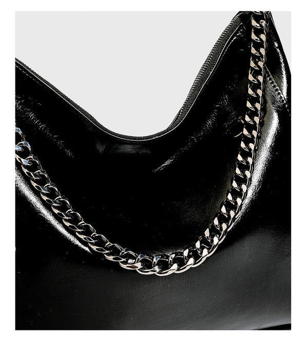 Slouchy hobo shoulder bag with glossy leather-look finish, silver-tone chain drape across front, side buckle pockets, and