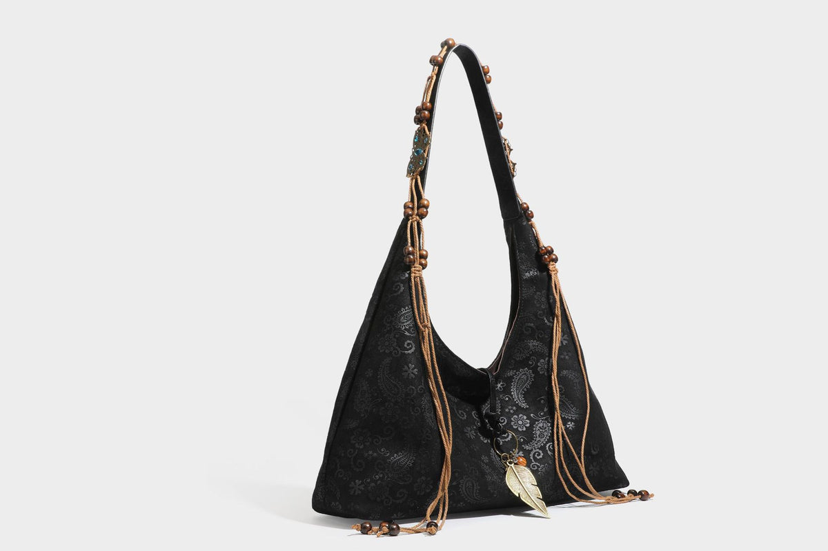 Slouchy boho hobo shoulder bag in embossed brown suede-look finish with beaded strap, cord tassels, and brass-tone leaf